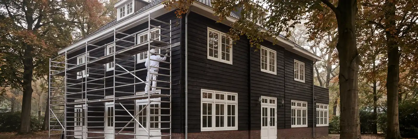 Grote vrijstaande woning met donkere houten gevelbekleding en steiger in Bloemendaal